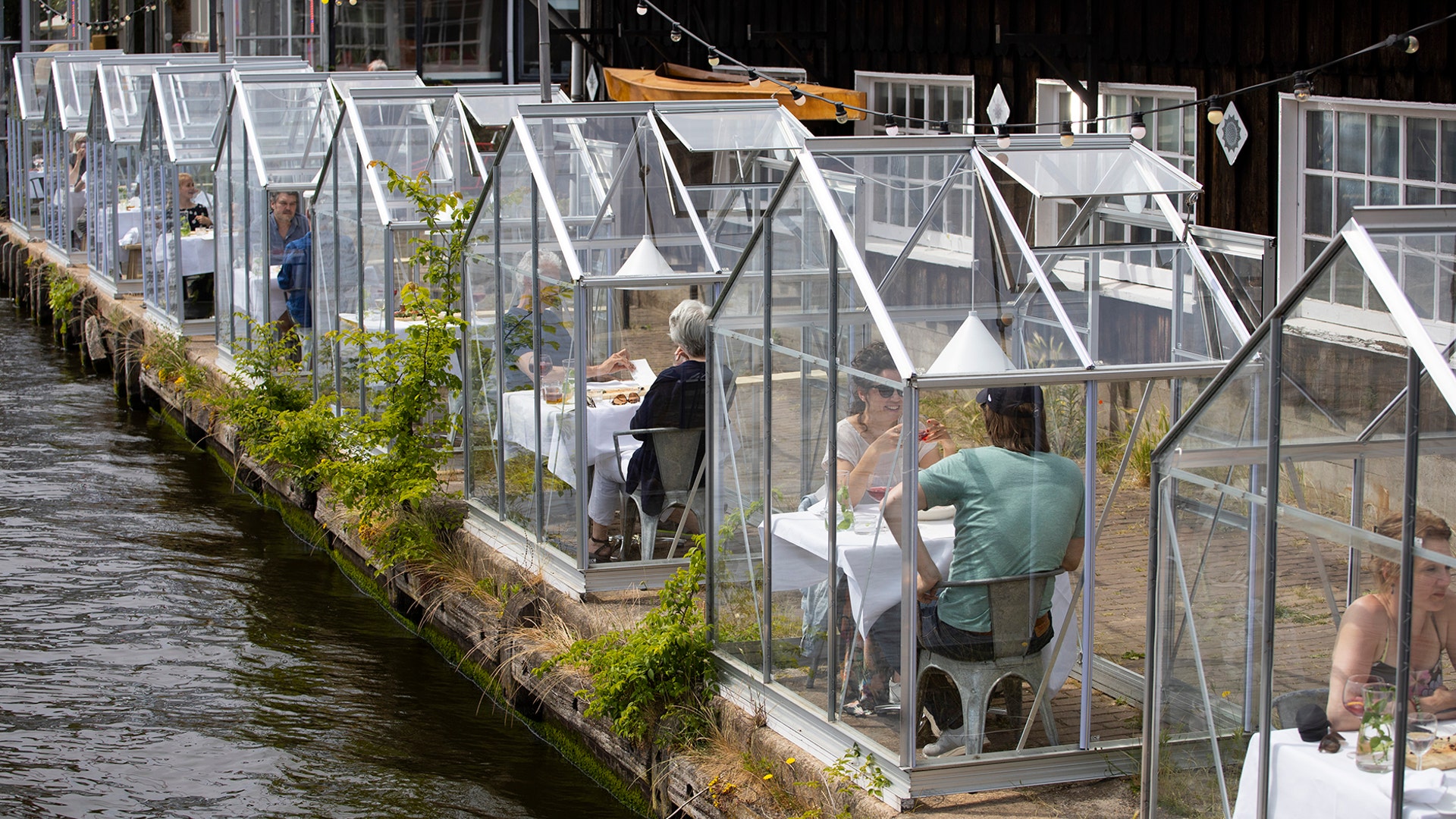 Customers seated in small glasshouses enjoy lunch at the Mediamatic restaurant in Amsterdam, Netherlands, June 1, 2020.