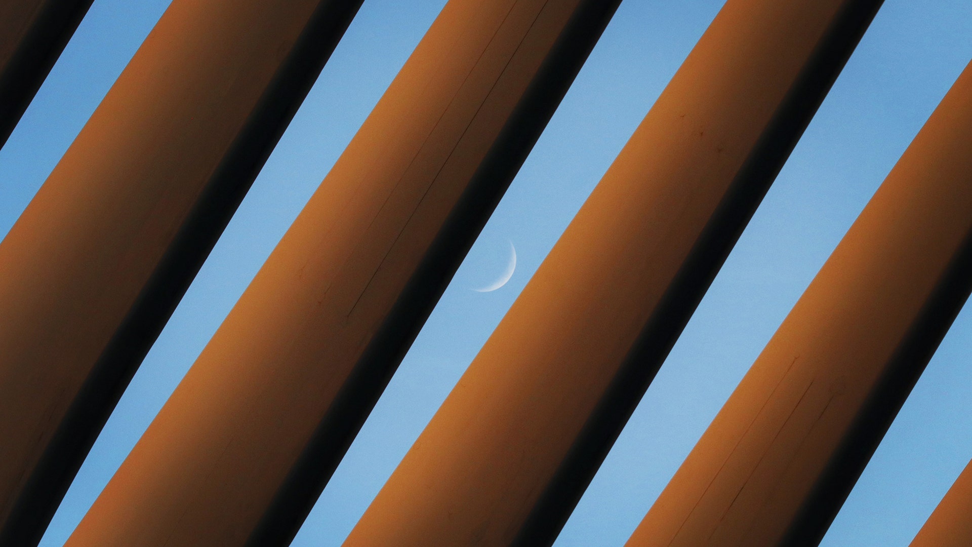 A crescent moon sets in the sky behind the roof of the Oculus transit hub in New York City, June 24, 2020.