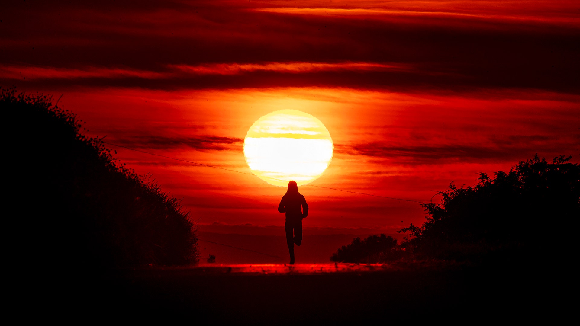 A woman runs on a road as the sun rises in Frankfurt, Germany, June 21, 2020. 