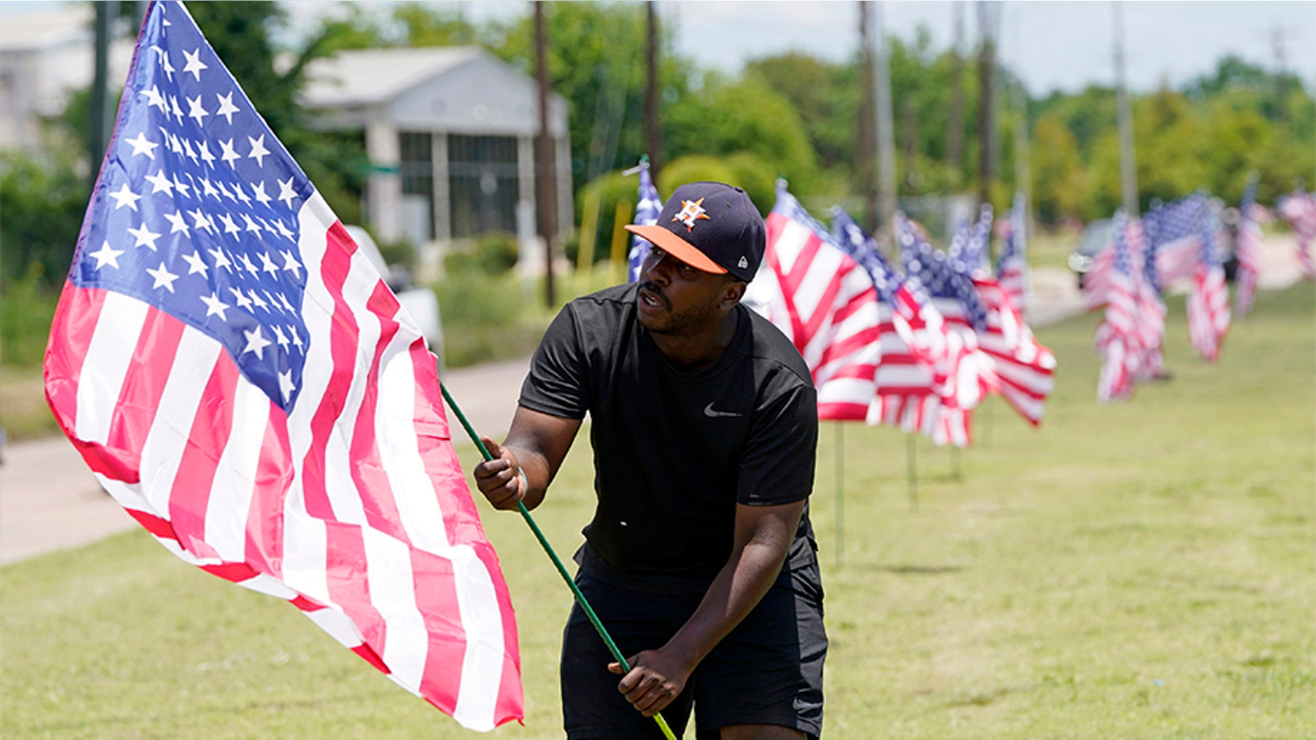 Bryan Smart planting American flags along Hillcroft Ave. as he walks toward The Fountain of Praise church in Houston.