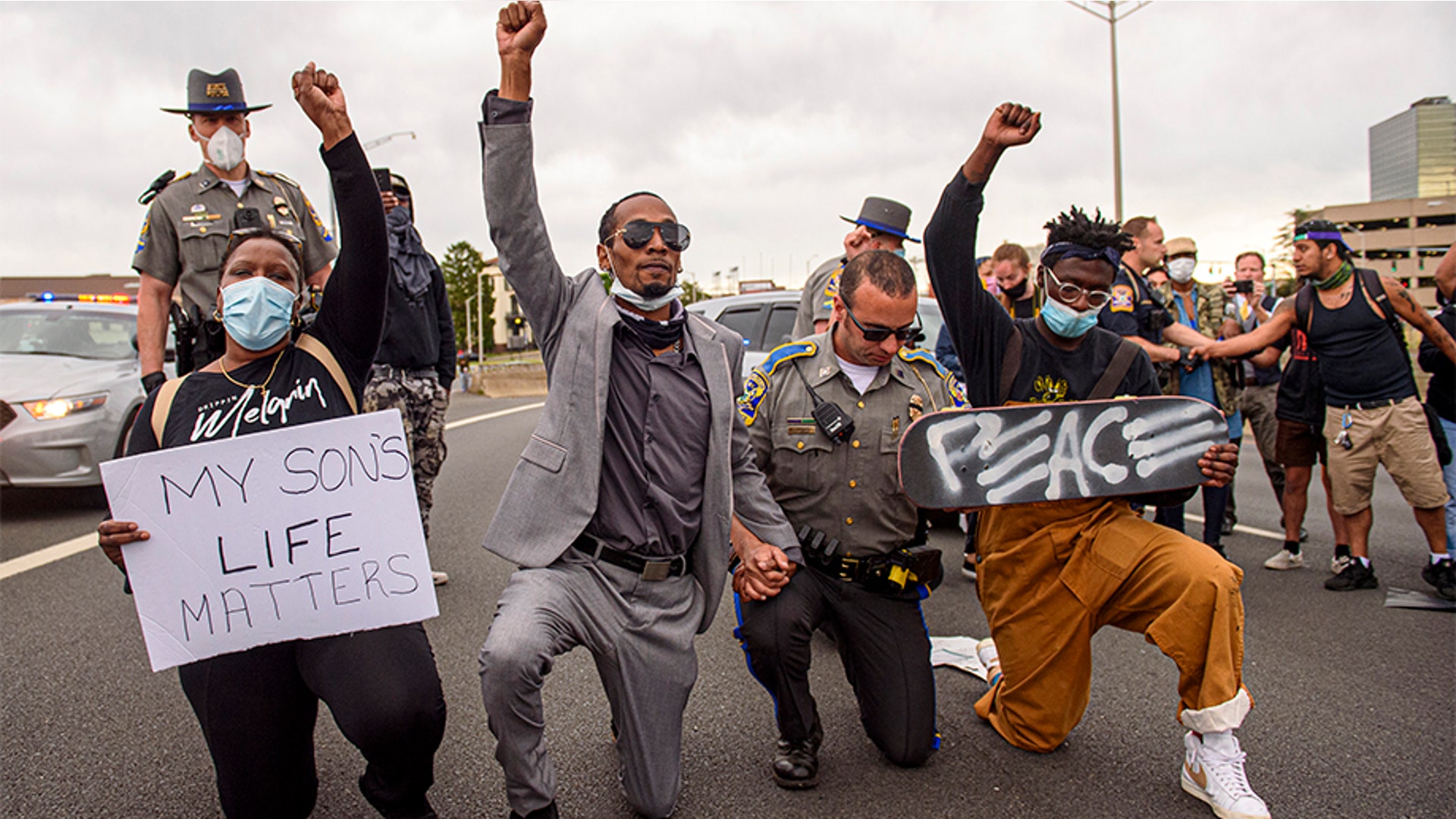 Demonstrators including Abimbola Oretadu, second from left, and David Walker kneeling with a Connecticut state trooper in Hartford.