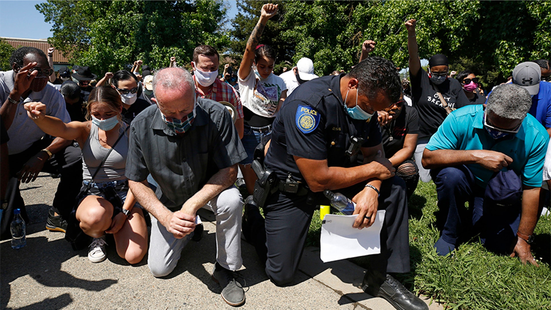Sacramento Mayor Darrell Steinberg, foreground left, and Sacramento Police Chief Daniel Hahn, foreground right, kneeling with others for a moment of silence at a rally in honor of George Floyd on June 3.