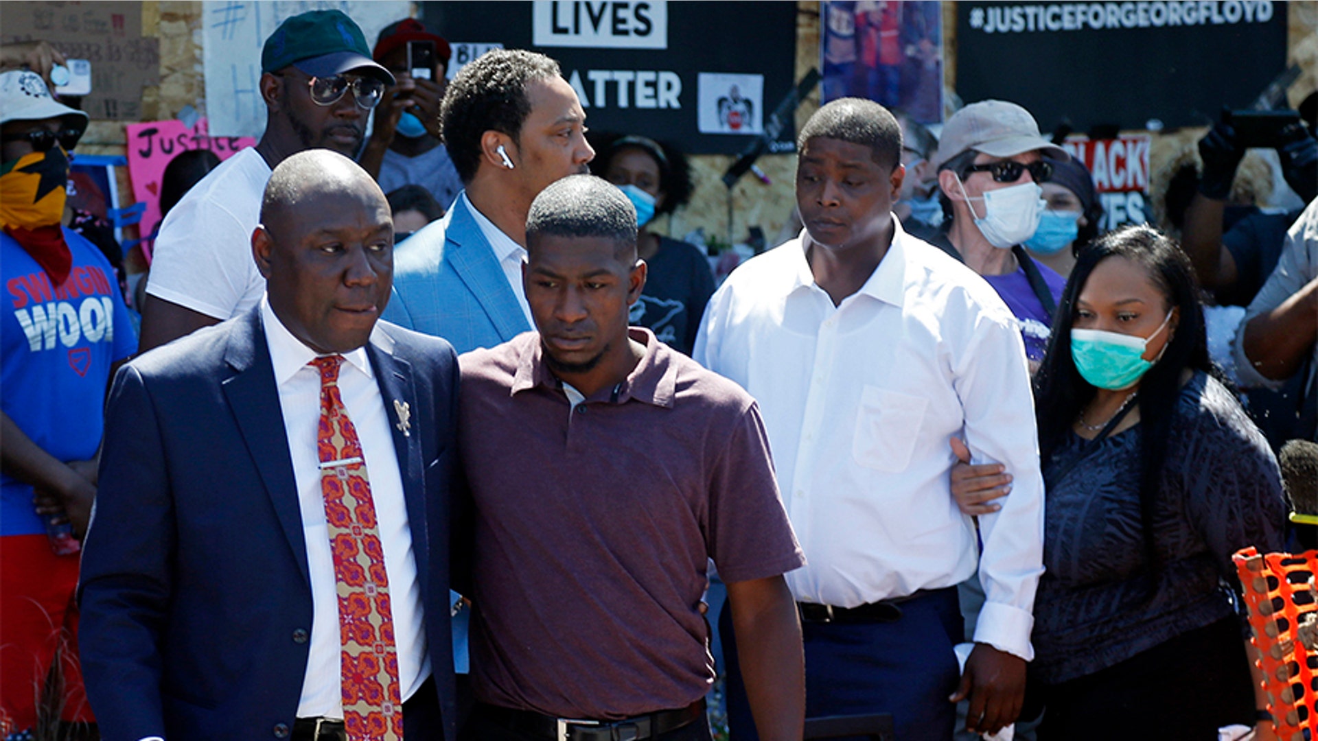 Family attorney Ben Crump, left, escorting Quincy Mason, second from left, a son of George Floyd, as they and some Floyd family members visited a memorial where Floyd died.