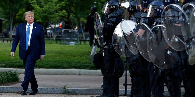 President Donald Trump walks past police in Lafayette Park after he visited outside St. John's Church across from the White House Monday, June 1, 2020, in Washington. Part of the church was set on fire during protests on Sunday night. (AP Photo/Patrick Semansky)