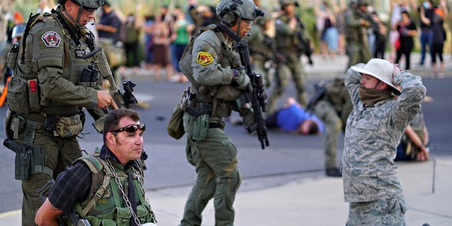 Albuquerque police detain members of the New Mexico Civil Guard, an armed civilian group, following the shooting of a man during a protest over a statue of Spanish conquerer Juan de Oñate on Monday, June 15, 2020, in Albuquerque, N.M. A confrontation erupted between protesters and a group of armed men who were trying to protect the statue before protesters wrapped a chain around it and began tugging on it while chanting: “Tear it down.” One protester repeatedly swung a pickax at the base of the statue. Moments later a few gunshots could be heard down the street and people started yelling that someone had been shot. (Adolphe Pierre-Louis/The Albuquerque Journal via AP)