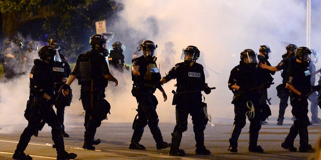 Charlotte-Mecklenburg Police Department officers begin to move forward through tear gas during a protest, Saturday, May 30, 2020, in Charlotte, N.C., as people nationwide protested the Memorial Day death of George Floyd, who died in police custody in Minneapolis. (Jeff Siner/The Charlotte Observer via AP)