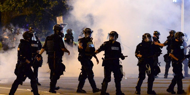 Charlotte-Mecklenburg Police Department officers begin to move forward through tear gas during a protest, Saturday, May 30, 2020, in Charlotte, N.C., as people nationwide protested the Memorial Day death of George Floyd, who died in police custody in Minneapolis. (Jeff Siner/The Charlotte Observer via AP)