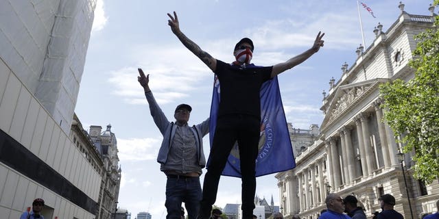 Members of Football Lads Alliance, standing at a police barrier along Whitehall, in central London, chant slogans, Saturday, June 13, 2020.