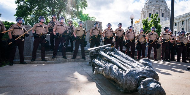 Minnesota State Troopers surrounded the statue of Christopher Columbus after it was toppled in front of the Minnesota State Capitol, Wednesday, June 10, 2020, in St. Paul, Minn. The statue was later towed away. (Leila Navidi/Star Tribune via AP)