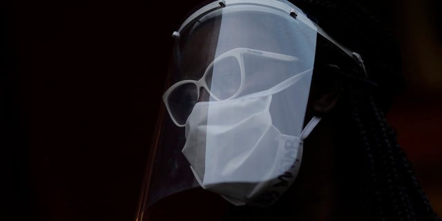 A woman wearing a face mask and shield to protect from the spread of the new coronavirus in Duque de Caxias, Brazil, Wednesday, June 10, 2020. (AP Photo/Silvia Izquierdo)