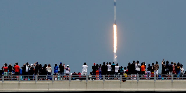 Spectators watch from a bridge in Titusville, Fla., as SpaceX Falcon 9 lifts off with NASA astronauts Doug Hurley and Bob Behnken in the Dragon crew capsule, Saturday, May 30, 2020, from the Kennedy Space Center at Cape Canaveral, Fla.  (AP Photo/Charlie Riedel)