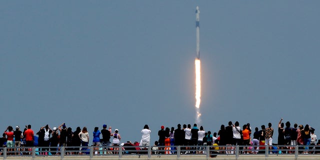 Spectators watch from a bridge in Titusville, Fla., as SpaceX Falcon 9 lifts off with NASA astronauts Doug Hurley and Bob Behnken in the Dragon crew capsule, Saturday, May 30, 2020, from the Kennedy Space Center at Cape Canaveral, Fla.  (AP Photo/Charlie Riedel)