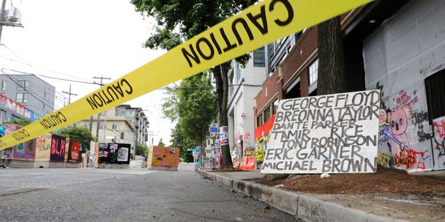Caution tape is shown near a sign with the names of victims of police violence, Saturday, June 20, 2020, at the Capitol Hill Occupied Protest zone in Seattle.