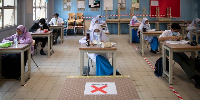 Students wearing face masks and maintaining social distancing at a classroom during the first day of school reopening at a high school in Putrajaya, Malaysia, Wednesday, June 24, 2020. Malaysia began reopening schools Wednesday while entering the Recovery Movement Control Order (RMCO) after three months of coronavirus restrictions. (AP Photo/Vincent Thian)