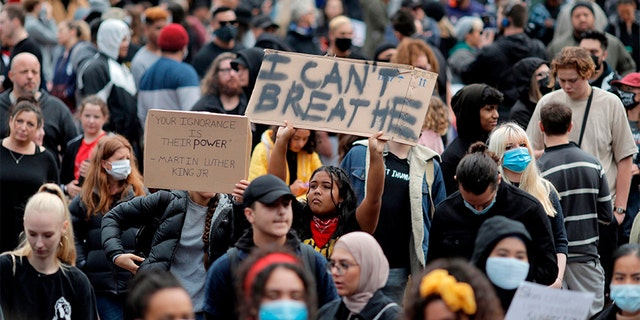 Demonstrators hold placards during a march in central Auckland, New Zealand, Monday, June 1, 2020, to protest the death of United States' George Floyd, a black man who died in police custody in Minneapolis on May 25. Floyd, who after a white police officer who is now charged with murder, Derek Chauvin, pressed his knee into Floyd's neck for several minutes even after he stopped moving and pleading for air. (Dean Purcell/New Zealand Herald via AP)