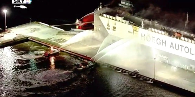 In this image made from aerial video taken on June 4, 2020, firefighters spray a cargo ship with water, in Jacksonville, Florida. Authorities say nine firefighters responding to a fire aboard a ship in Florida have been hospitalized after the ship exploded. The ship, a Norwegian vessel called Hoegh Xiamen was carrying old and used cars and had been scheduled to leave Jacksonville, First Coast News reported. (WJXT via AP)