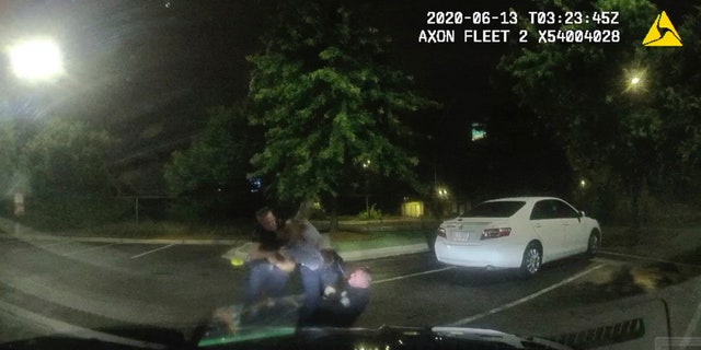 This screen grab taken from dashboard camera video provided by the Atlanta Police Department shows Rayshard Brooks, center, struggling with Officers Garrett Rolfe, left, and Devin Brosnan in the parking lot of a Wendy's restaurant, early Saturday, June 13, 2020, in Atlanta. (Atlanta Police Department via AP)