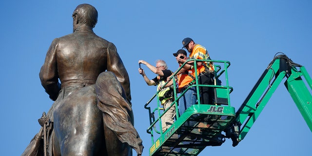 An inspection crew from the Virginia Department of General Services inspect the statue of Confederate Gen. Robert E. Lee on Monument Avenue June 8, in Richmond, Va. Virginia Gov. Ralph Northam has ordered the removal of the statue. (AP Photo/Steve Helber)