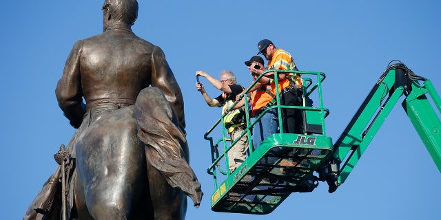 An inspection crew from the Virginia Department of General Services inspect the statue of Confederate Gen. Robert E. Lee on Monument Avenue June 8, in Richmond, Va. Virginia Gov. Ralph Northam has ordered the removal of the statue. (AP Photo/Steve Helber)