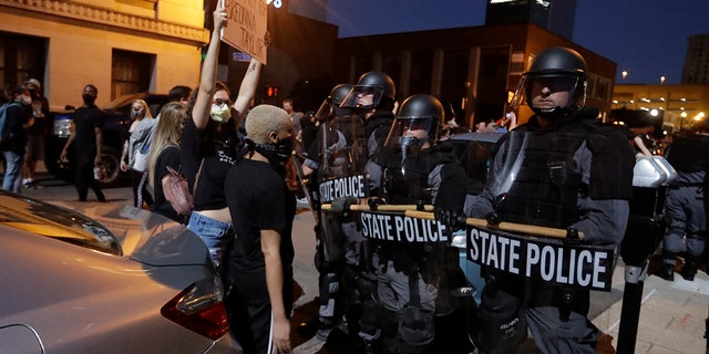 Protesters shout in front of Kentucky State Police officers as they protest the deaths of George Floyd and Breonna Taylor, Friday, May 29, 2020, in Louisville, Ky. Breonna Taylor, a black woman, was fatally shot by police in her home in March. (AP Photo/Darron Cummings)