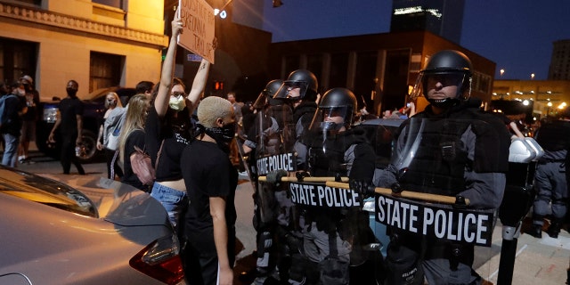 Protesters shout in front of Kentucky State Police officers as they protest the deaths of George Floyd and Breonna Taylor, Friday, May 29, 2020, in Louisville, Ky. Breonna Taylor, a black woman, was fatally shot by police in her home in March. (AP Photo/Darron Cummings)