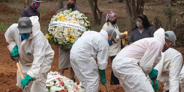 Relatives watch cemetery workers shovel dirt over the coffin of 47-year-old Paulo Roberto da Silva, who died of COVID-19, at the Sao Luiz cemetery in Sao Paulo, Brazil, Thursday, June 4, 2020. (AP Photo/Andre Penner)
