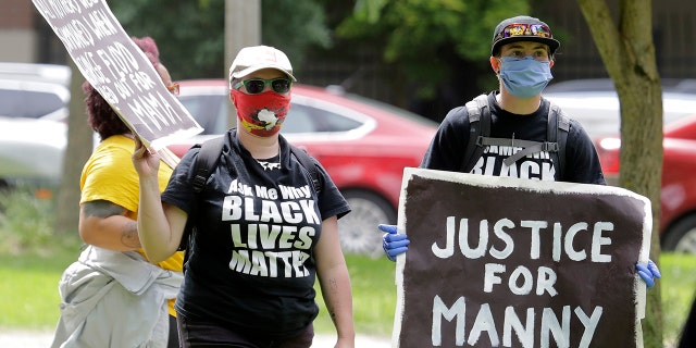 A protester holds a sign that reads "Justice for Manny" on June 5, in Tacoma, Wash., during a protest against police brutality and the death of George Floyd, a black man who died after being restrained by Minneapolis police officers on May 25. Ellis died March 3 while being held down by Tacoma police. (AP Photo/Ted S. Warren)