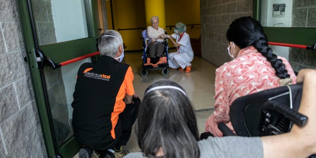 Albina Minelli, 92, sits on a wheelchair as he she talks from safety distance with her parents, and is flanked by Maria Giulia Badaschi, health director, at the elderly nursing home Fondazione Martino Zanchi, in Alzano Lombardo, Italy, May 29. (AP Photo/Luca Bruno)
