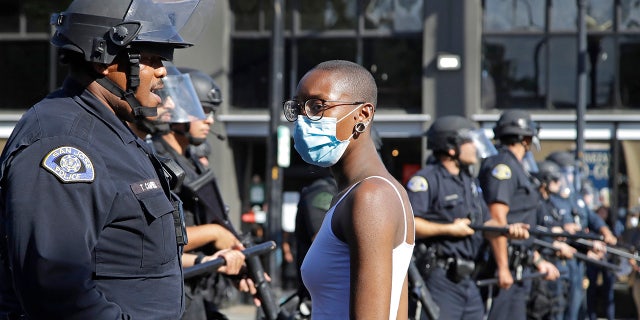 A masked woman speaks with a San Jose police officer while protesting on Friday, May 29, 2020, in San Jose, Calif. (AP Photo/Ben Margot)