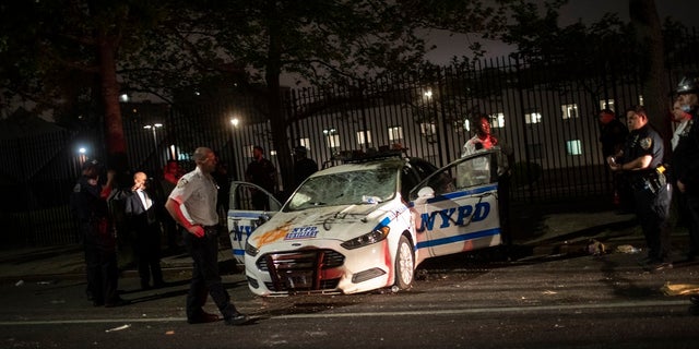 Policemen surround an NYPD vehicle after it was vandalized by protestors over the death of George Floyd, a black man who was in police custody in Minneapolis, on Saturday in the Brooklyn borough of New York. Floyd died after being restrained by Minneapolis police officers on Memorial Day. (AP Photo/Wong Maye-E)