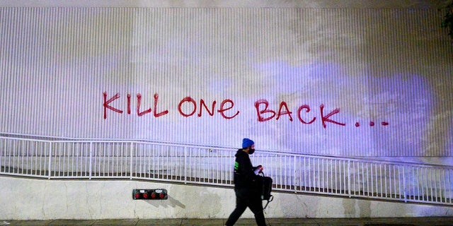 A demonstrator passes graffiti in Oakland, Calif. while protesting the death of George Floyd. (AP Photo/Noah Berger)
