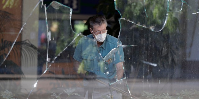 A worker vacuums broken glass from storefront in downtown Louisville, Ky. , Saturday, May 30, 2020. The store was damaged Friday evening during a protest over the deaths of George Floyd and Breonna Taylor. (AP Photo/Darron Cummings)