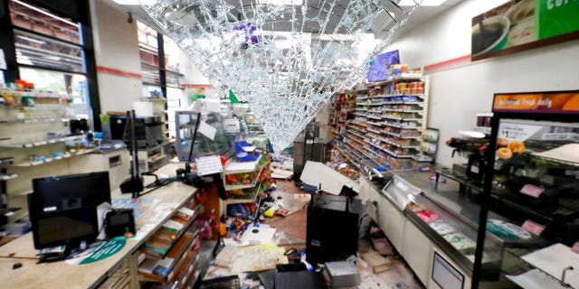 Shattered glass hangs from the doorway of a 7-Eleven store May 31, 2020, in Chicago. (AP Photo/Charles Rex Arbogast)