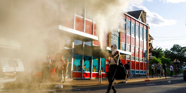 A person shoots a fire extinguisher into the air as he walks though a street in Upper Darby, Pa. on Sunday May 31, 2020, as people move through streets in protest over the death of George Floyd, a black man who was in police custody in Minneapolis. Floyd died after being restrained by Minneapolis police officers on Memorial Day, May 25. (AP Photo/Matt Slocum)