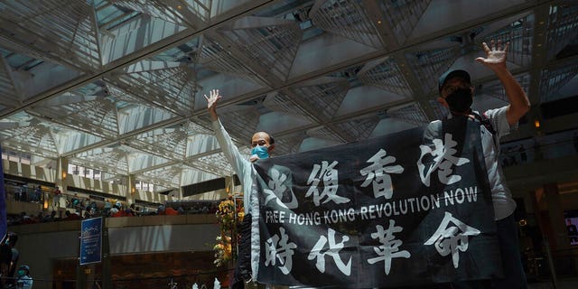 Protesters gesture with five fingers, signifying the "Five demands - not one less" in a shopping mall during a protest against China's national security legislation for the city, in Hong Kong, Monday, June 1, 2020. 