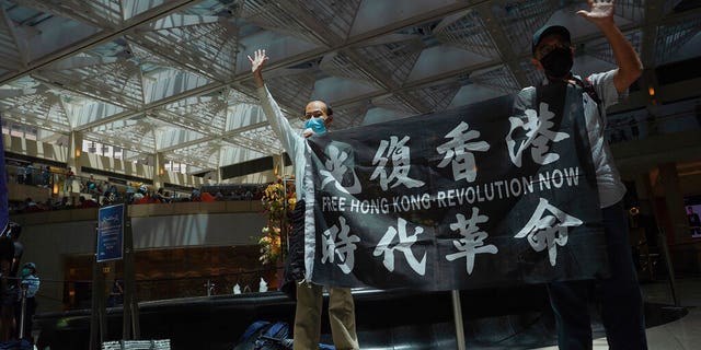 Protesters gesture with five fingers, signifying the "Five demands - not one less" in a shopping mall during a protest against China's national security legislation for the city, in Hong Kong, Monday, June 1, 2020. 