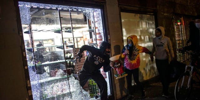 People run out of a broken-into smoke shop in New York City early Monday as police arrive. (AP)