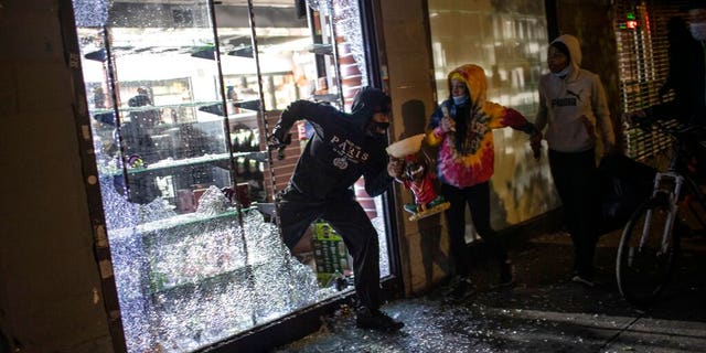 People run out of a broken-into smoke shop in New York City early Monday as police arrive. (AP)