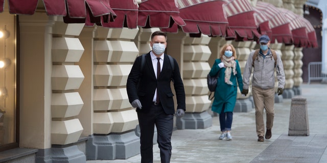 People wearing face masks and gloves to protect from coronavirus, walk to an entrance of the GUM, State Department store after reopening in Moscow, Russia, on Monday, June 1, 2020. Monday's reopening of retail stores along with dry cleaners and repair shops comes as the pace of contagion has stabilized in the Russian capital that has accounted for about half of the nation's infections.