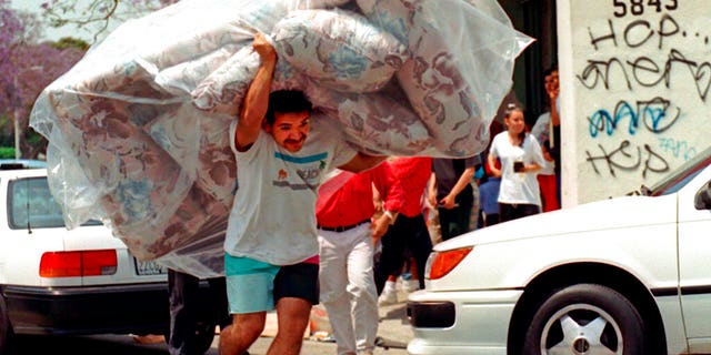 FILE: A man removes a couch from a store in South Central Los Angeles following verdicts in the Rodney King beating trial. 