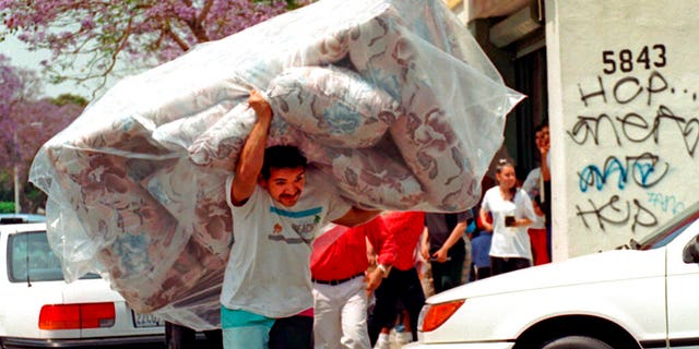 FILE: A man removes a couch from a store in South Central Los Angeles following verdicts in the Rodney King beating trial.