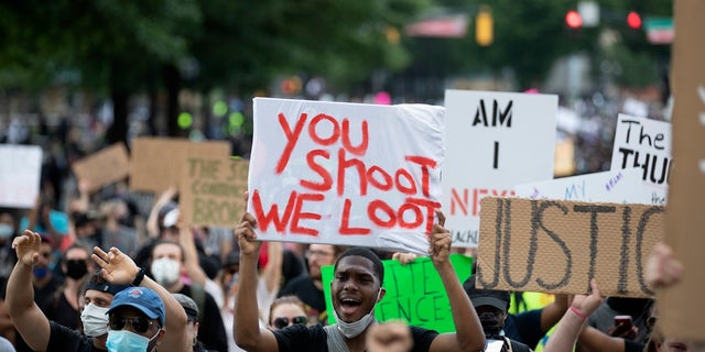 People carry signs as they march Monday, June 1, 2020, in Atlanta during a demonstration over the death of George Floyd, who died after being restrained by Minneapolis police officers on May 25. (AP Photo/John Bazemore).