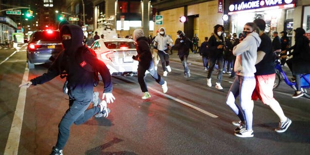 People being chased by police run past pedestrians near Union Square, Monday, June 1, 2020, in New York