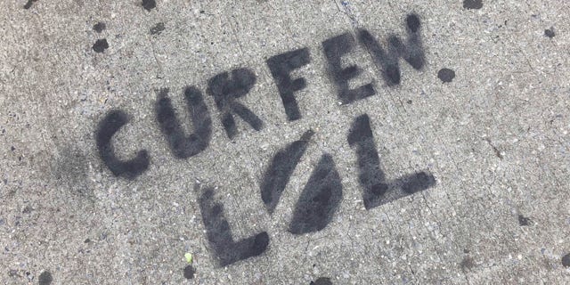 A sidewalk is spray painted with graffiti about New York City's curfew order, in the Brooklyn borough of New York, Tuesday, June 2, 2020. (AP Photo/Mark Lennihan)