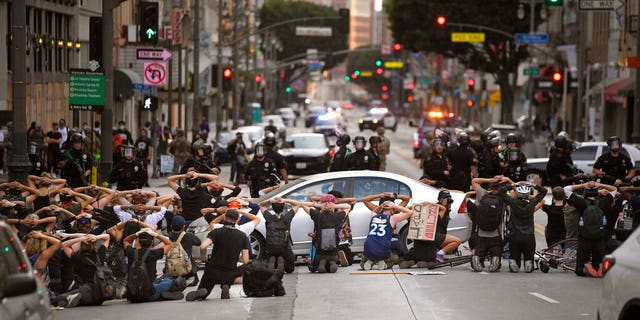 Demonstrators put their hands behind their heads before being taken into custody after the city's curfew went into effect following a protest, Tuesday, June 2, 2020, in Los Angeles over the death of George Floyd. 