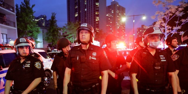 New York City police officers watch protesters calling for justice over the death of George Floyd, Wednesday, June 3, 2020, in the Brooklyn borough of New York. Floyd died after being restrained by Minneapolis police officers on May 25. (AP Photo/Frank Franklin II)