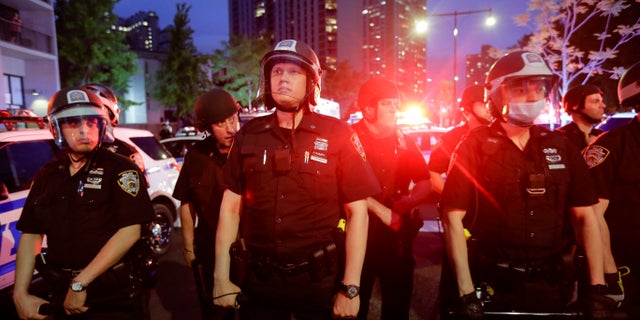 New York City police officers watch protesters calling for justice over the death of George Floyd, Wednesday, June 3, 2020, in the Brooklyn borough of New York. Floyd died after being restrained by Minneapolis police officers on May 25. (AP Photo/Frank Franklin II)