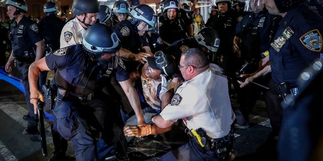 A protester is arrested on Fifth Avenue by NYPD officers during a march last week in the Manhattan. (AP Photo/John Minchillo)