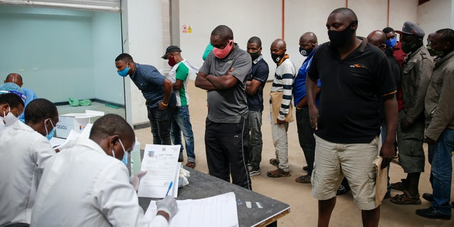 In this photo taken Monday, June 1, 2020, truck drivers entering Kenya queue to be tested for the coronavirus on the Kenya side of the Namanga border crossing with Tanzania. Africa's long-haul truckers carry food, fuel and other essential supplies along dangerous roads, but now they say they are increasingly accused of carrying the coronavirus as well. The drivers say they are stigmatized and even threatened in some countries. (AP Photo/Brian Inganga)