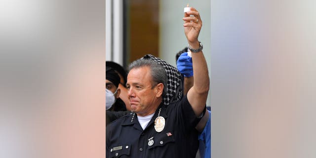 Los Angeles Police Department Chief Michel Moore holds up an electric candle as speaks during a vigil with members of professional associations and the interfaith community at LAPD headquarters, Friday, June 5, 2020, in Los Angeles. (AP Photo/Mark J. Terrill)